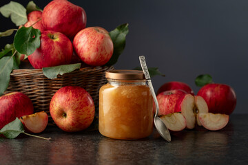 Apple jam and fresh apples on a black stone table.