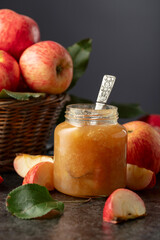 Apple jam and fresh apples on a black stone table.