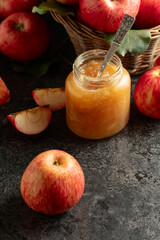 Apple jam and fresh apples on a black stone table.