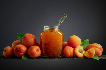 Apricot jam in glass jar and fresh fruits.