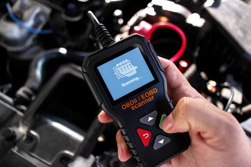OBDII Scanner in use under the hood by auto mechanic for reading fault code of the car engine...