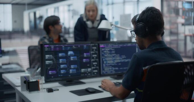 Indian Cyber Security Engineer Working on a Computer with Multiple Screens in a Software Development in an Artificial Intelligence Company. Specialist Working Behind a Desk. Footage from the Back