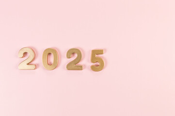 2025 Happy New Year. Top view of gold numbers on pink background. Copy space, flat lay.