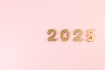 2025 Happy New Year. Top view of gold numbers on pink background. Copy space, flat lay.