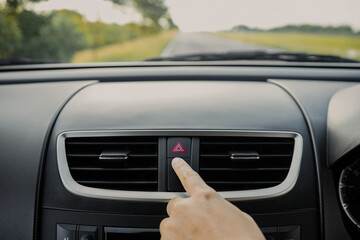 Close up of hand of a young woman  driver is pressing the emergency button on the dashboard of the...