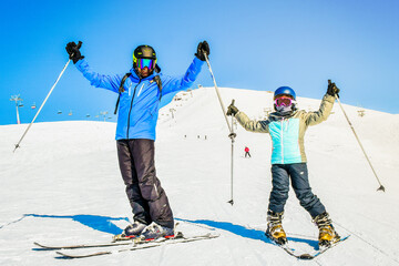 Skiing family enjoying winter vacation on snow in sunny cold day in mountains and fun. Two skiers...