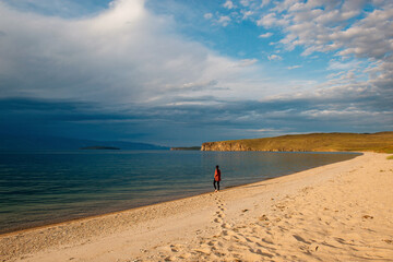 a girl walks along the shore of Lake Baikal