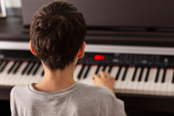 Rear view of boy playing digital piano