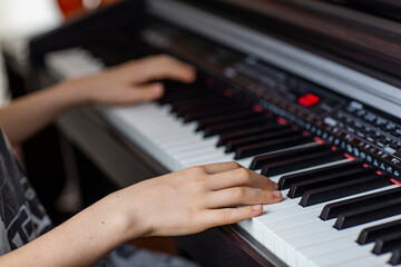 Obraz premium Close-up image of child's hands playing digital piano at home