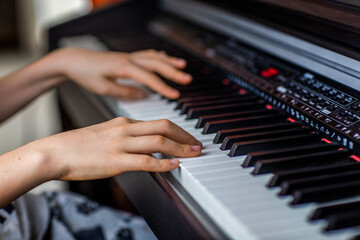 Obraz premium Close-up image of child's hands playing digital piano at home