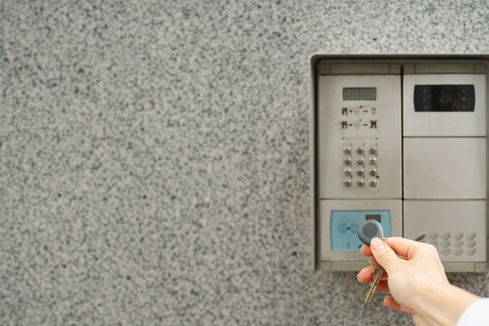 Woman's hand with key fob against intercom