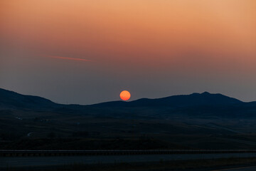 Orange sun at dusk in a smoky Montana sky