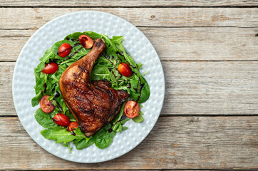 Grilled chicken legs with tomatoes and salad . Top view