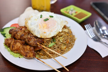 Indonesian fried rice with chicken satay and sunny side up egg on top