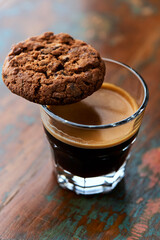 Chocolate cookie and Coffee in glass cup on rustic wooden background. Close up.