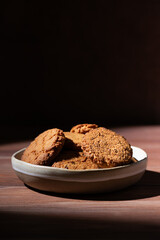 Oatmeal cookies tasty breakfast in the plate on a wooden table. Hard light. Vertical orientation.