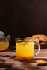 Sea buckthorn tea with orange and ginger with oatmeal cookies in a glass cups. Herbal vitamin tea. Hard light. Vertical orientation.