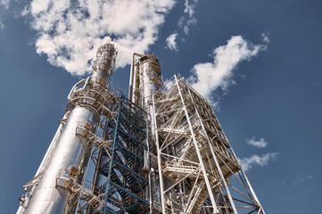 Distillation columns towering over a chemical plant under a bright sky during daylight operations