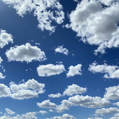 Fototapeta premium Vibrant Blue Sky with Fluffy White Clouds Illuminated by Sunlight, Perfect for Seasonal and Nature Themes in Creative Projects and Designs