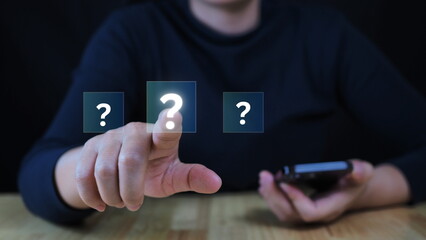 Question mark shows on a palm, Businessman show question mark icon, Technology question concept, FAQ on a virtual screen while standing on a black background.