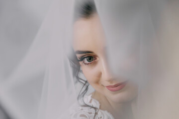 A woman with long hair and a veil is looking at the camera. She has a smile on her face and her...