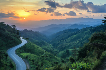 winding road with a beautiful sunset in the background. The road is surrounded by lush green hills and trees. The scene is serene and peaceful, with the sun setting in the distance
