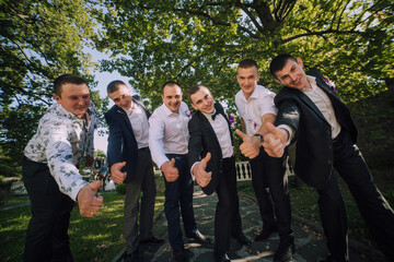 A group of men are posing for a picture, all wearing suits and giving thumbs up. Scene is positive and celebratory, as the men are likely congratulating each other or celebrating a special occasion