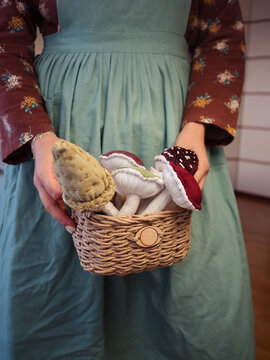 Woman in Vintage Apron Holding a Basket with Handmade Plush Mushrooms
