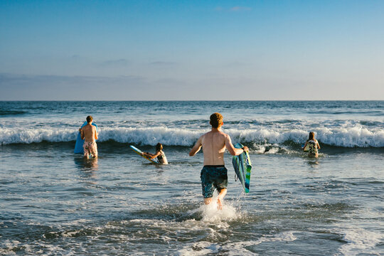 Teenage boy runs out to family members in ocean through waves
