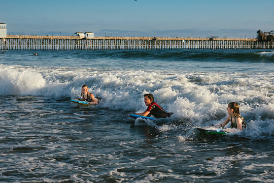 Siblings laughing together on body boards riding on waves in ocean