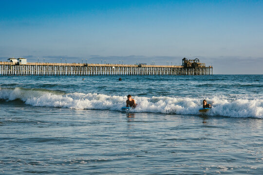 Brother and sister catch wave together on body boards in ocean