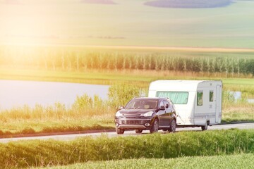 Vehicle hauling caravan through green landscape