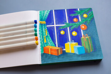 Drawing with markers in a sketchbook on the Christmas theme - a Christmas tree with decorations and gifts