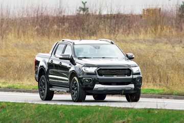 Sleek black pickup driving on a suburban road