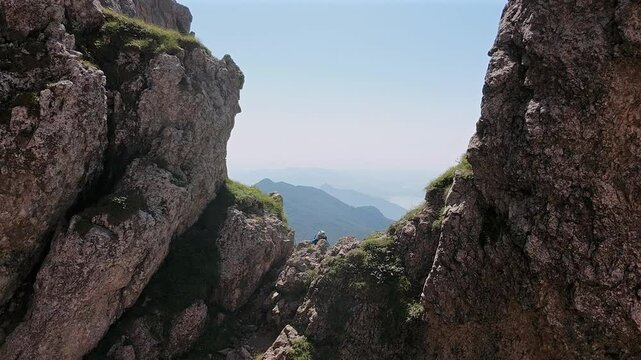 Drone flying at low altitude over man climbs rocky mountain, dangerous passages, summer, Grignetta, Italian Alps. Aerial forward