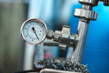 A pressure gauge is attached to a metal pipe in a factory setting