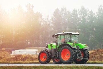 Green tractor traveling on asphalt road in countryside