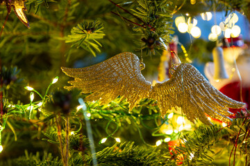 Golden glittery angel wings tree ornament Christmas tree decoration. Festive fairy lights. Symbolic.