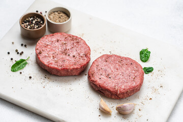 Raw piece of steakburger on marble board with spices. Marbled beef for making burger