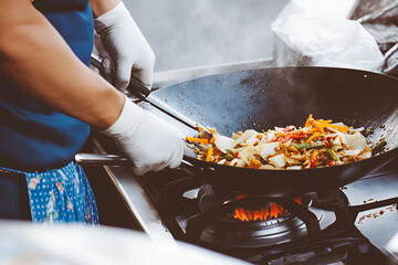 Chef cooking pad thai in a large wok street food stall food photography urban kitchen close-up culinary art