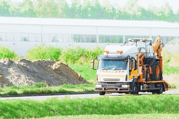 Tow truck with mini excavator on a highway on a sunny countryside summer day © AlexGo