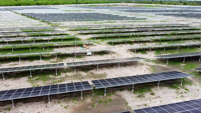 Aerial dolly rear view of clean new solar panels at solar park with visible DC combiner box