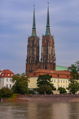 Naklejka premium Historic twin-spired cathedral in Wroclaw with rising river water levels after heavy rainfall on a cloudy day. Concept of climate impact and environmental awareness
