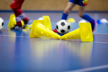 Indoor soccer young player with a soccer ball in a sports hall. Football futsal training for children. Sport background.