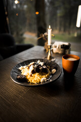 Mamaliga with cheese and smoked sausages on a black plate and a glass of kefir.Hominy dish.The concept of Moldavian cuisine