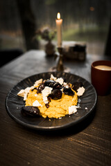 Mamaliga with cheese and smoked sausages on a black plate and a glass of kefir.Hominy dish.The concept of Moldavian cuisine