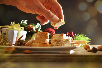 Hand picking up a portion of Christmas nougat from plate