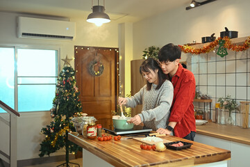 Fototapeta premium Romantic young couple preparing a meal together during Christmas season