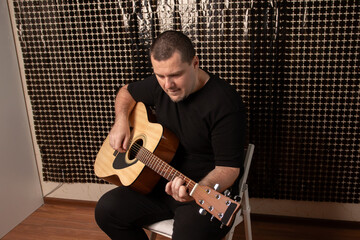 Man Playing Acoustic Guitar Indoors, performer strumming string, person practicing melody, studying...