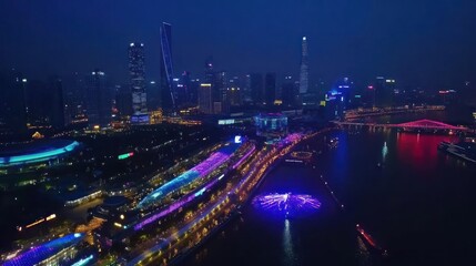 A vibrant city skyline illuminated at night, showcasing colorful lights along the river.
